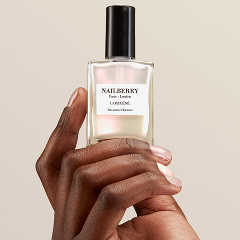 Hand holding a Nailberry perfume bottle against a beige background