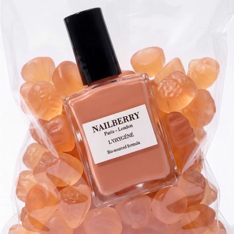 Nailberry nail polish bottle surrounded by orange gummy bears on a white background