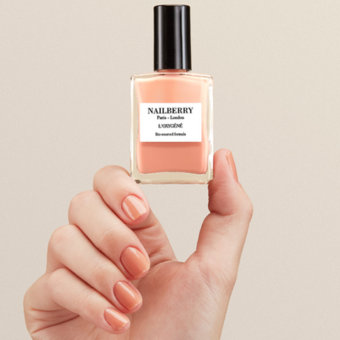 Hand holding a Nailberry perfume bottle with a beige background