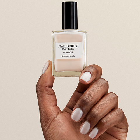 Hand holding a Nailberry nail polish bottle with a beige background